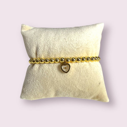 Elegant Mustard Seed Bracelet featuring gold beads and a heart charm, displayed on a soft pillow. Perfect gift!